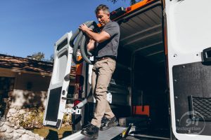 sewage removal technician carrying equipment out of van